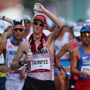 Evan Dunffee se verse une bouteille d'eau sur la tête pendant l'épreuve à Tokyo.