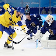 Le joueur suédois tente un tir contre le gardien finlandais. 