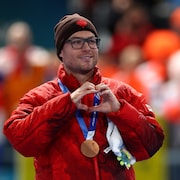 Il forme un cœur avec ses mains en regardant vers la foule.