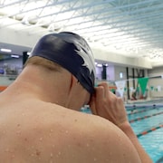Un nageur met un casque sur sa tête près d’une piscine.
