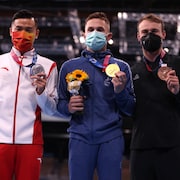 Trois athlètes avec des masques sanitaires montrent leurs médailles.
