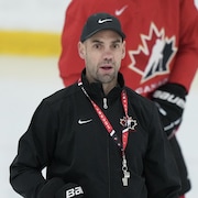 Un entraîneur de hockey sur la glace, sifflet au cou.