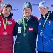 Trois skieurs, médaille au cou, regardent devant eux.
