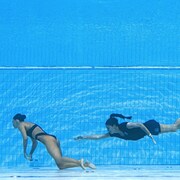 Une femme tente d'agripper une nageuse inconsciente sous l'eau.