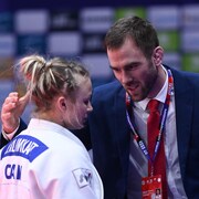 Un entraîneur console une judoka après sa défaite. 
