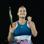 La joueuse de tennis Aryna Sabalenka sourit à pleines dents en serrant le poing gauche.