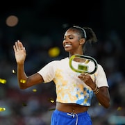 Masai Russell salue la foule en tenant son troph&eacute;e de la Diamond League.