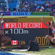 Le relais mixte canadien pose devant le tableau indicateur.