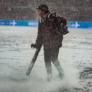 Un travailleur passe la souffleuse sur un terrain de soccer enneig&eacute; pendant une finale.