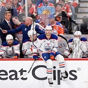 Connor McDavid est assis sur la bande au banc des Oilers.