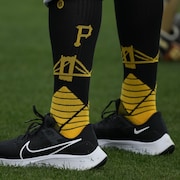 On aperçoit les mollets d'un joueur de baseball, qui porte des bas longs aux couleurs noir et jaune des Pirates.