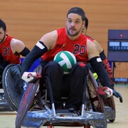 Un joueur en fauteuil roulant transporte un ballon de rugby.