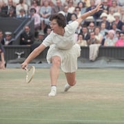 Une joueuse de tennis se penche et étire un bras pour frapper une balle.
