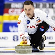 Le joueur de curling s'apprête à lancer une pierre.