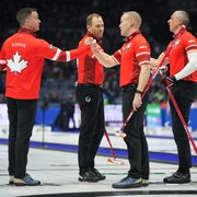 Quatre curleurs canadiens se félicitent après une victoire.