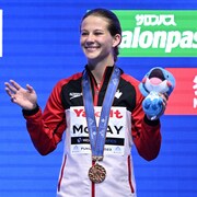 Caeli McKay, avec une veste aux couleurs de la délégation canadienne, salue la foule avec sa médaille de bronze, remportée au tremplin de 10 m lors des mondiaux de Fukuoka, au Japon