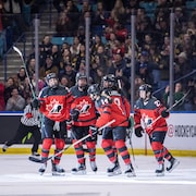 Des hockeyeuses canadiennes célèbrent un but.