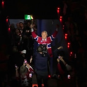 Un homme tient le flambeau et salue la foule en entrant dans le Centre Bell.