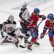 La rondelle entre dans le but pendant que le gardien a la vue voilée par des joueurs des deux équipes devant lui.