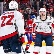 Un joueur de hockey crie de joie en regardant un coéquipier. 