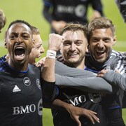 Des joueurs de soccer s'enlacent et sont heureux.