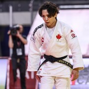Une judoka, épuisée par un combat, regarde devant elle. 