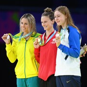 Les trois nageuses posent avec leurs médailles sur le podium.