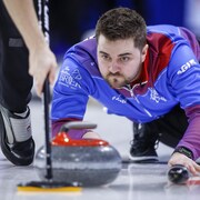 Matt Dunstone lance une pierre en se laissant glisser sur la glace.