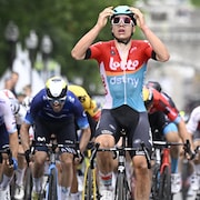 Il lève les bras vers son casque, l'air incrédule.
