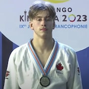 Un judoka avec sa médaille d'or est sérieux sur un podium.