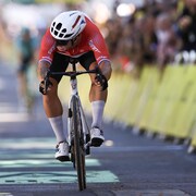 Un cycliste se penche sur son vélo en franchissant la ligne d'arrivée.