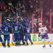 Des hockeyeurs célèbrent une victoire devant un rival ayant la tête baissée.