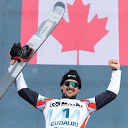 Un planchiste lève les bras au ciel. Le drapeau du Canada est projeté sur un écran derrière lui.