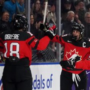Trois hockeyeuses représentant le Canada célèbrent un but.