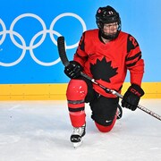 La hockeyeuse met un genou sur la glace. 
