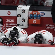 Trois hockeyeurs affichent leur déception au banc des joueurs.