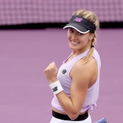 Une joueuse de tennis sourit et serre le poing après une victoire.