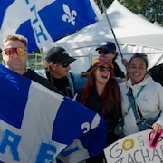 Cinq personnes sourient, entour&eacute;es de drapeaux du Qu&eacute;bec, c&eacute;l&egrave;brent apr&egrave;s la course du cycliste qu&eacute;b&eacute;cois Zachari Moreau.