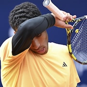 Un joueur de tennis s'essuie le front avec son avant-bras droit.