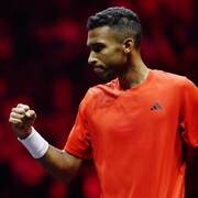 Un joueur de tennis, vêtu de rouge, montre le poing après avoir remporté un échange. 