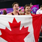 Ils tiennent un drapeau du Canada et d&eacute;bordent de joie.