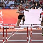 Femke Bol saute par dessus une haie lors d'une course.