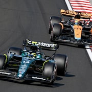 Deux monoplaces de F1 se suivent sur un circuit et s'apprêtent à tourner à droite.