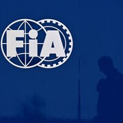 On voit la silhouette d'une personne qui marche le long d'un mur orné du sigle de la FIA.