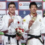 Des judokas sourient sur un podium et montrent leurs médailles.