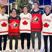 Cinq hockeyeurs qui portent un chandail de l'équipe canadienne posent pour la photo.