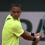 Le joueur de tennis frappe la balle du revers.