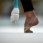 Gros plan du pied d'une gymnaste, avec deux objets blancs et bleus tout près.
