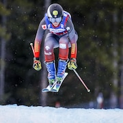Une skieuse se prépare à atterrir après un saut lors d'une course de ski cross.