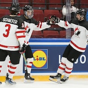 Trois joueurs d'équipe Canada célèbrent.